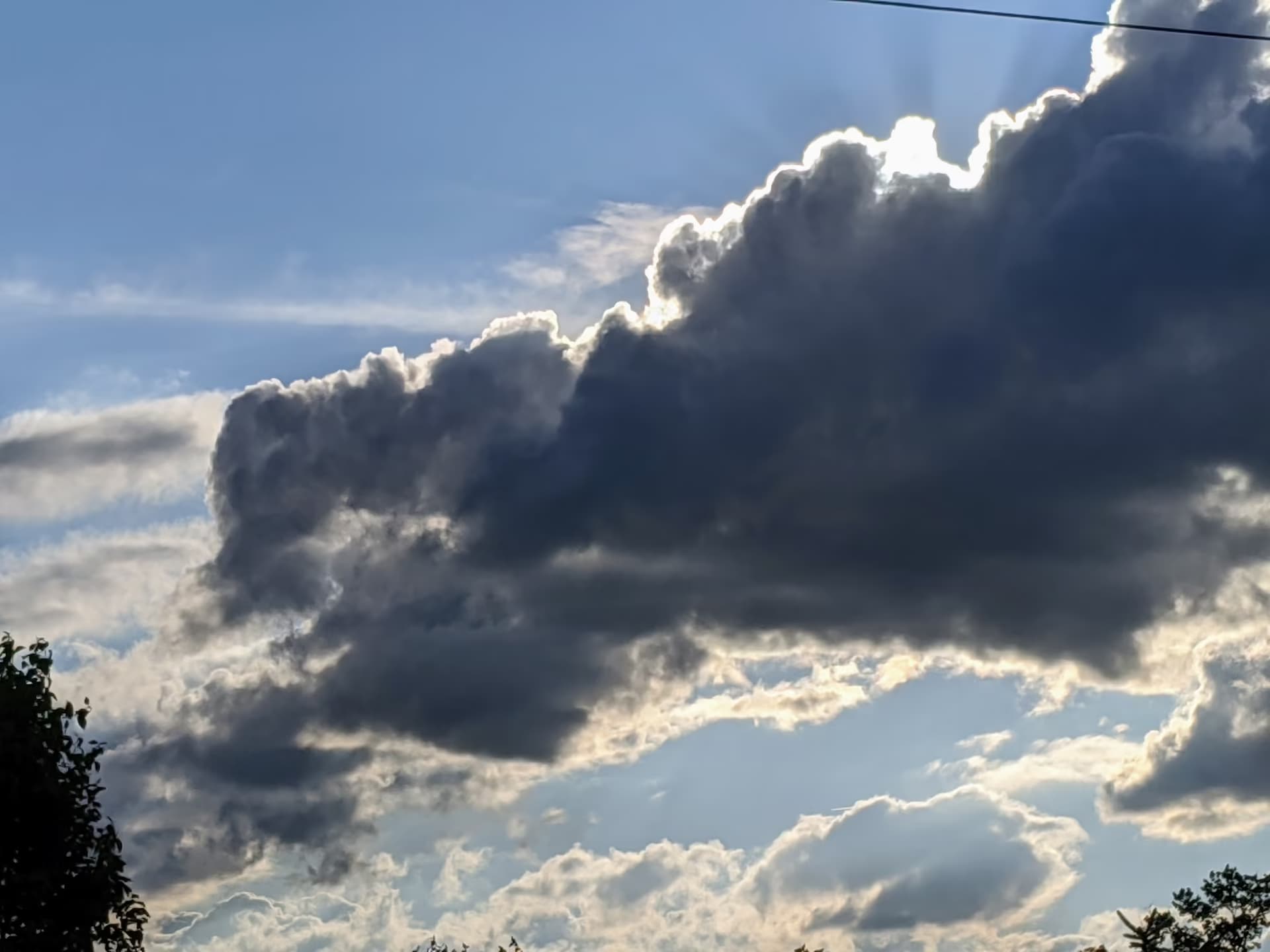 Photo of a blue sky with fluffy white/gray clouds in front in the evening.